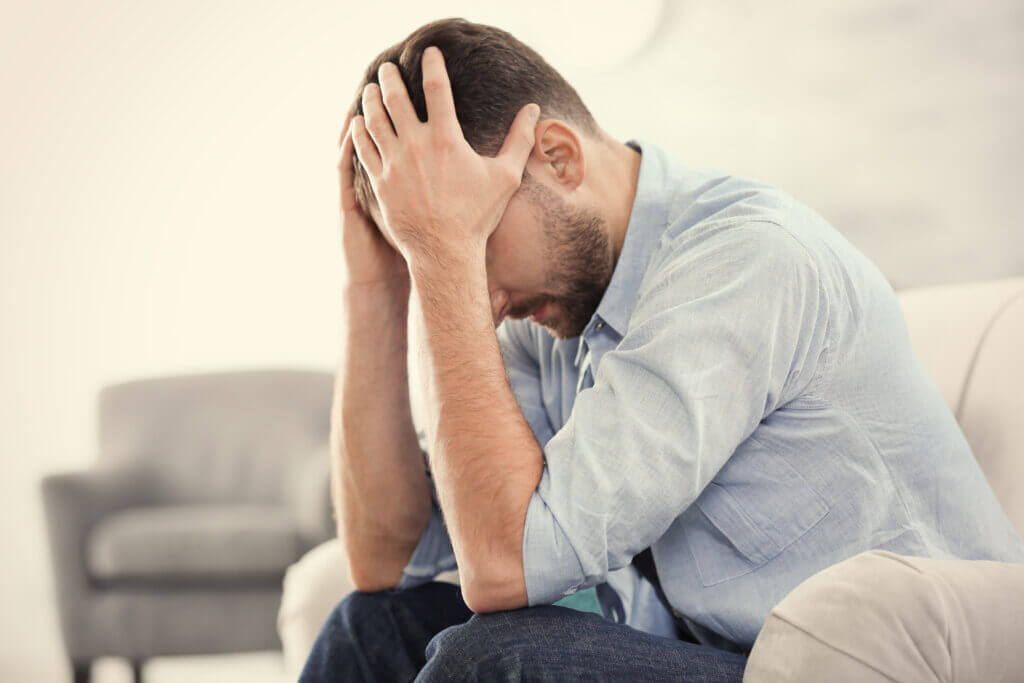 Handsome depressed man sitting on sofa at home