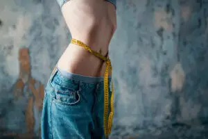 Thin woman in jeans measures waist, weight loss