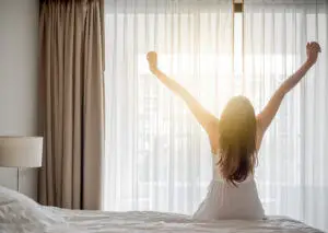 Asian woman wake up in the morning, sitting on white bed