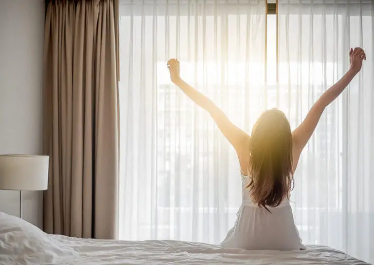 Asian woman wake up in the morning, sitting on white bed