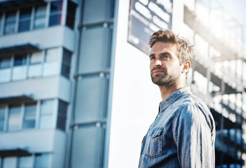 Man with ADHD looking upwards in front of buildings in Las Vegas after receiving psychiatric treatment at MindWell