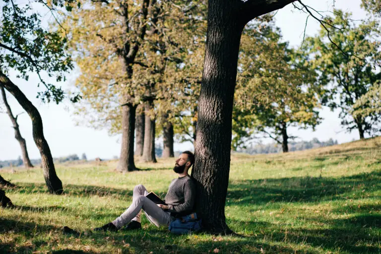 young man sitting against tree in las vegas feeling depressed despite summer sun needing to go to mindwell psychiatric services