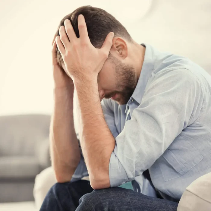 Handsome depressed man sitting on sofa at home