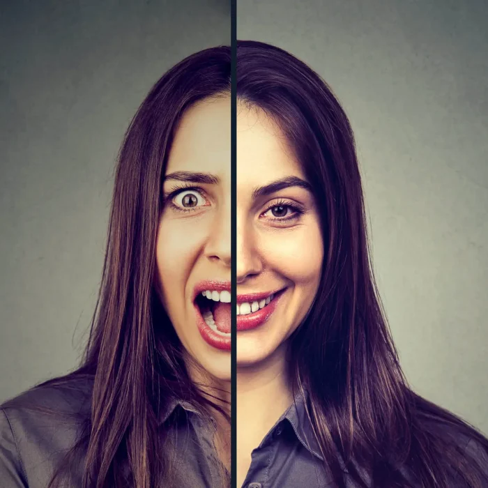 Bipolar disorder and split personality concept. Woman with double face expression isolated on gray background
